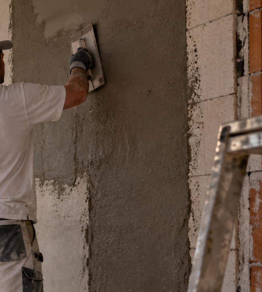 Hand mit Reibebrett zieht frischen Putz auf die Wand